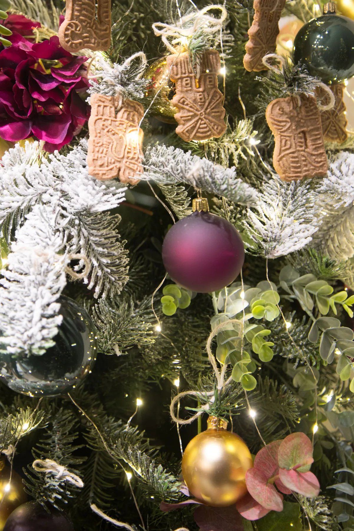A close-up of a Christmas tree adorned with golden balls and decorative cookies.