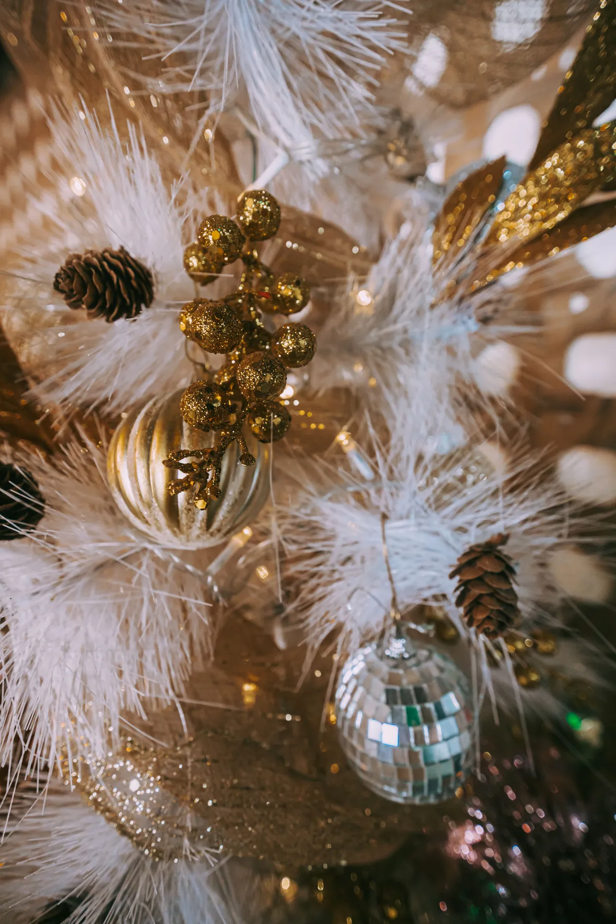 A detailed shot of a Christmas tree adorned with gold and silver ornaments and glittering lights, creating a festive atmosphere.