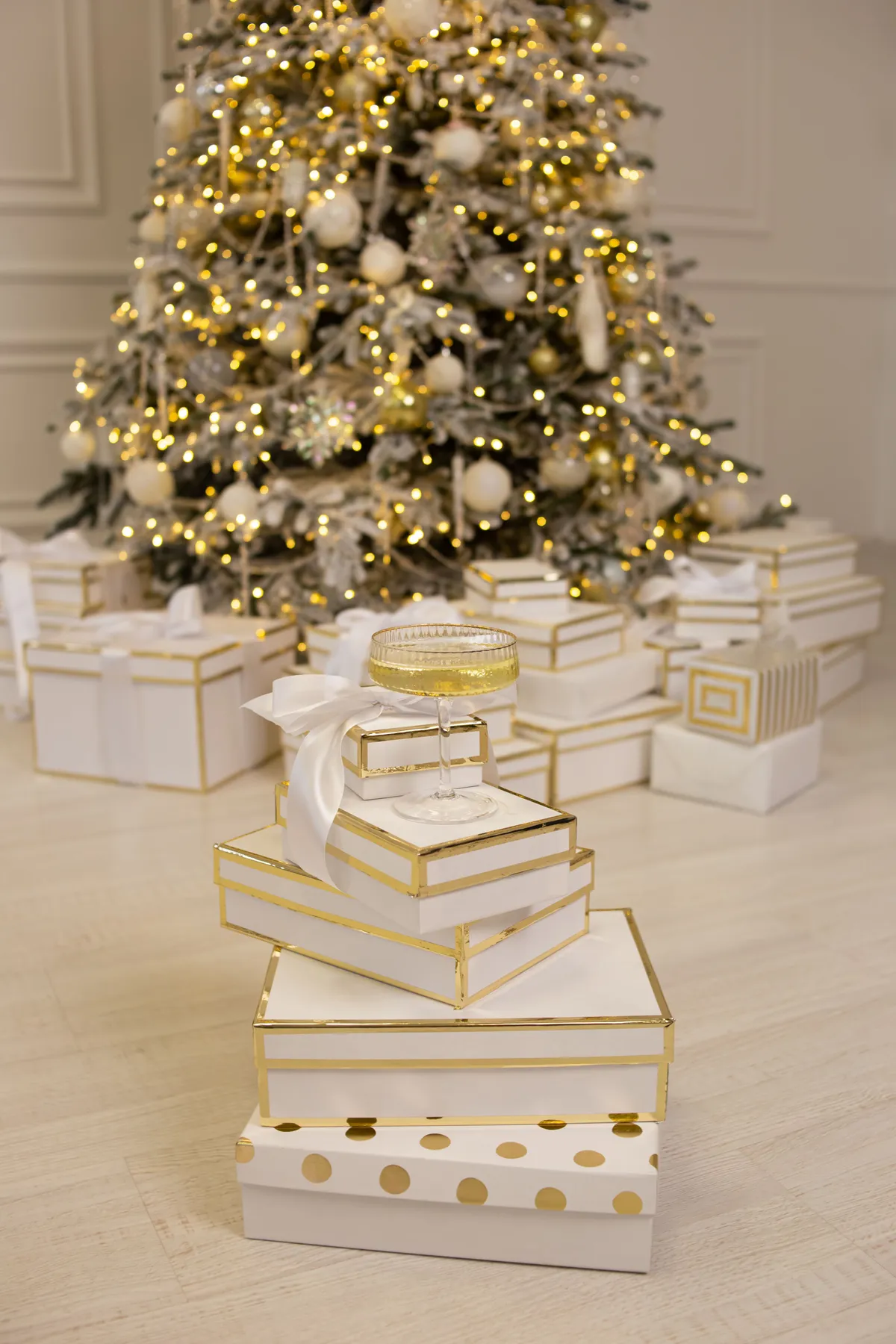 A festive Christmas setting featuring a decorated tree and elegantly wrapped gifts with champagne glass.