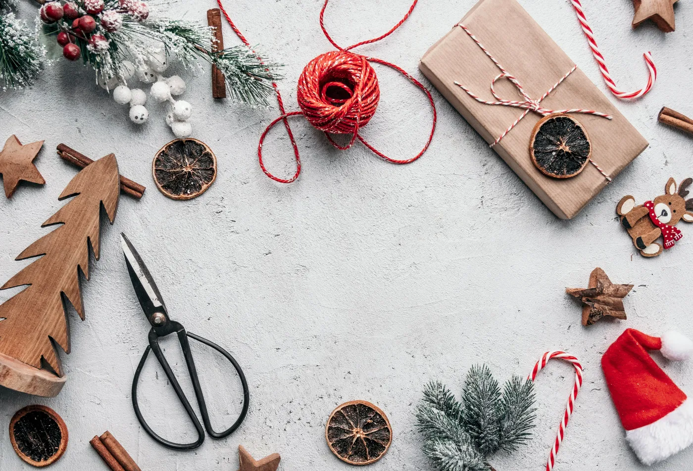 A festive flat lay with Christmas decorations and gift wrapping elements on a rustic surface.