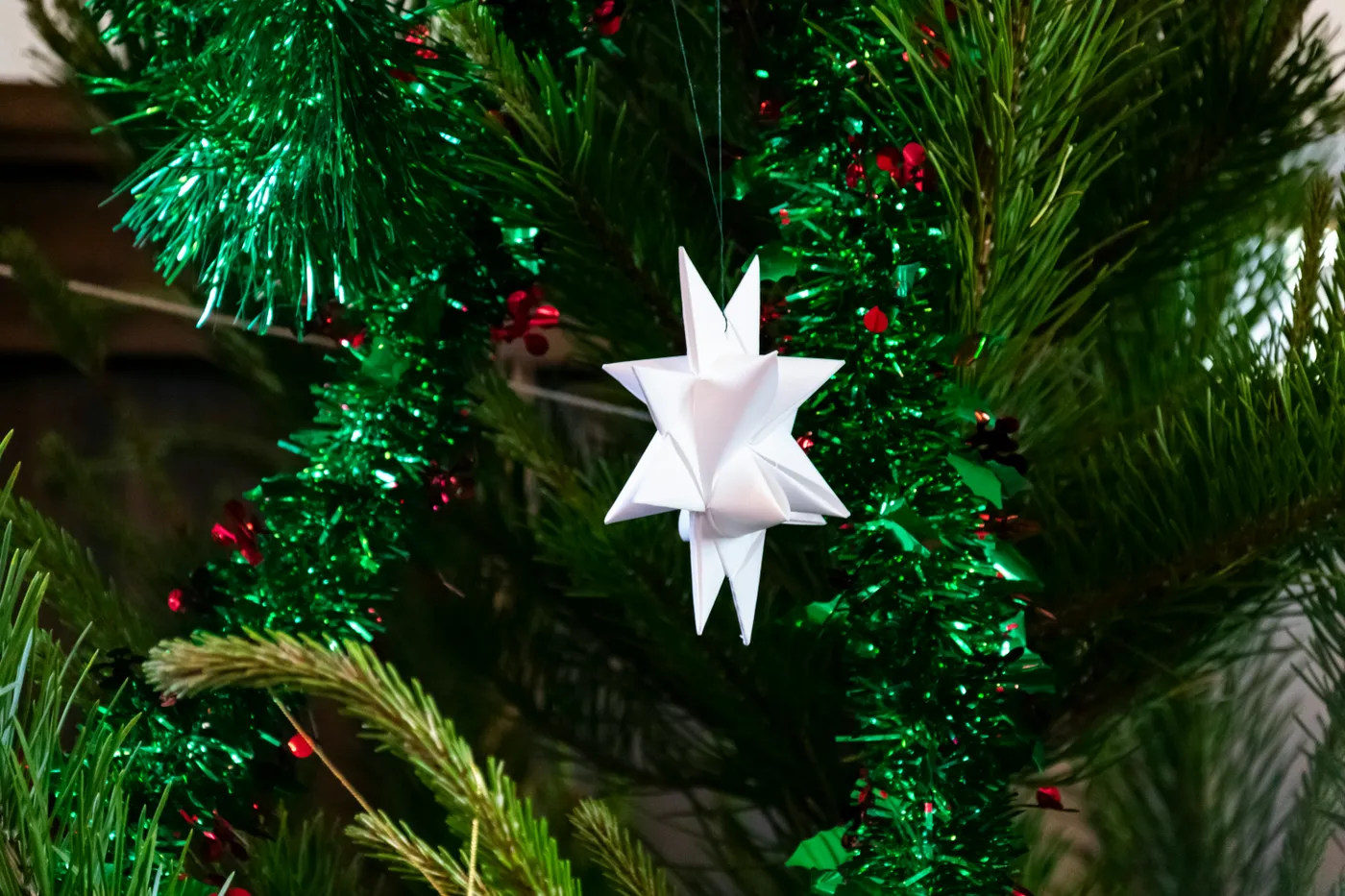 a white origami star hanging from a christmas tree