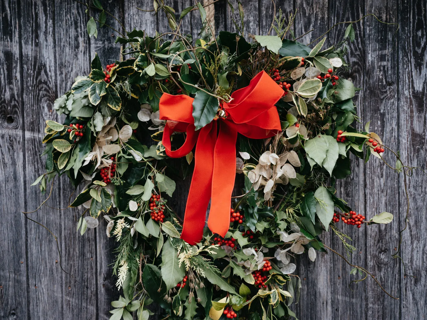 A wreath with a red bow hanging on a wooden fence - Free Photo on Unsplash