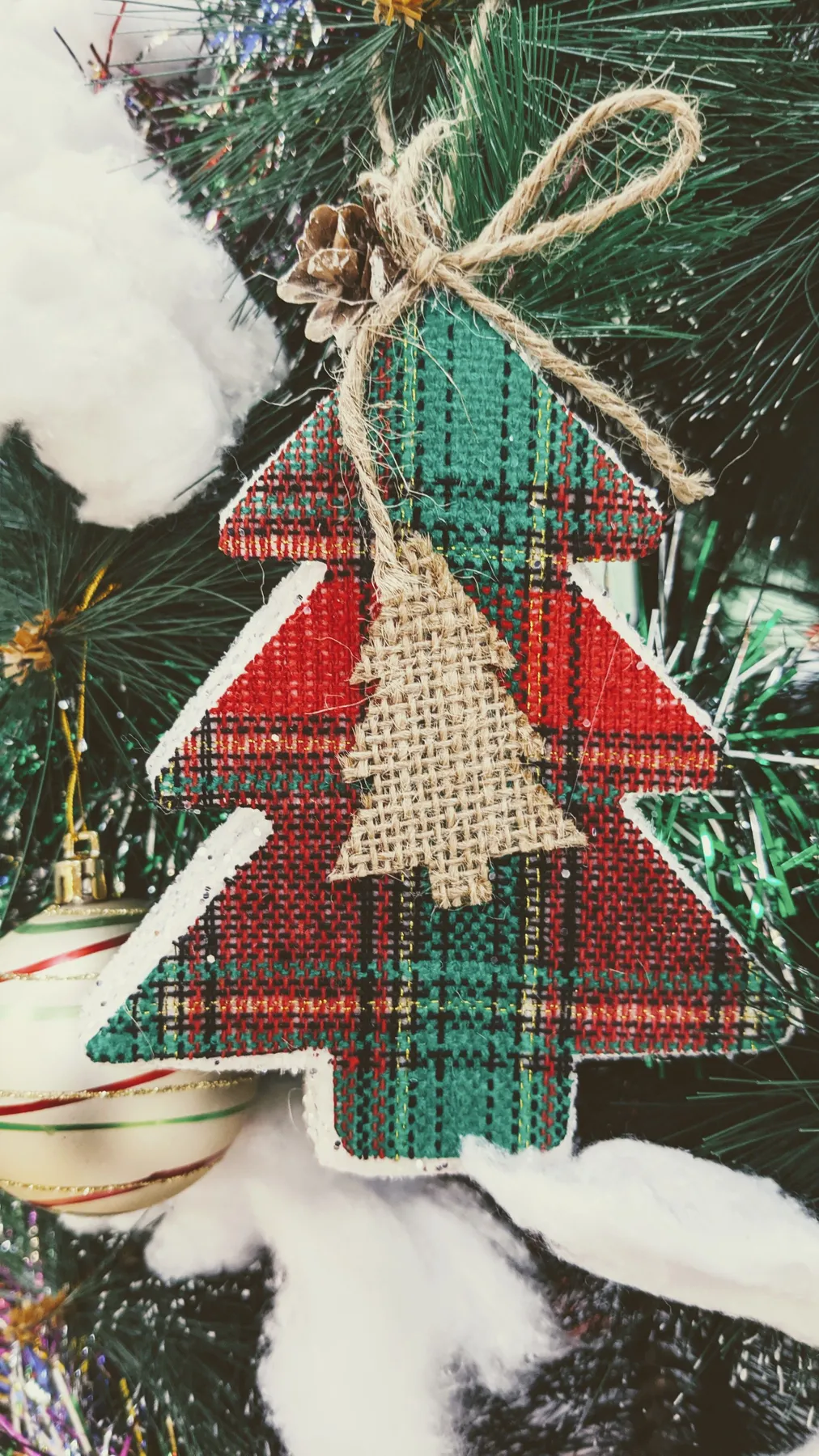 Artistic handmade Christmas tree ornament on a decorative green Christmas tree branch.