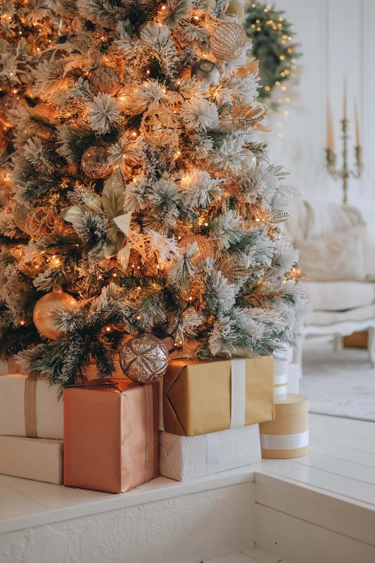 Beautifully decorated Christmas tree with gifts and warm lights in a cozy indoor setting.