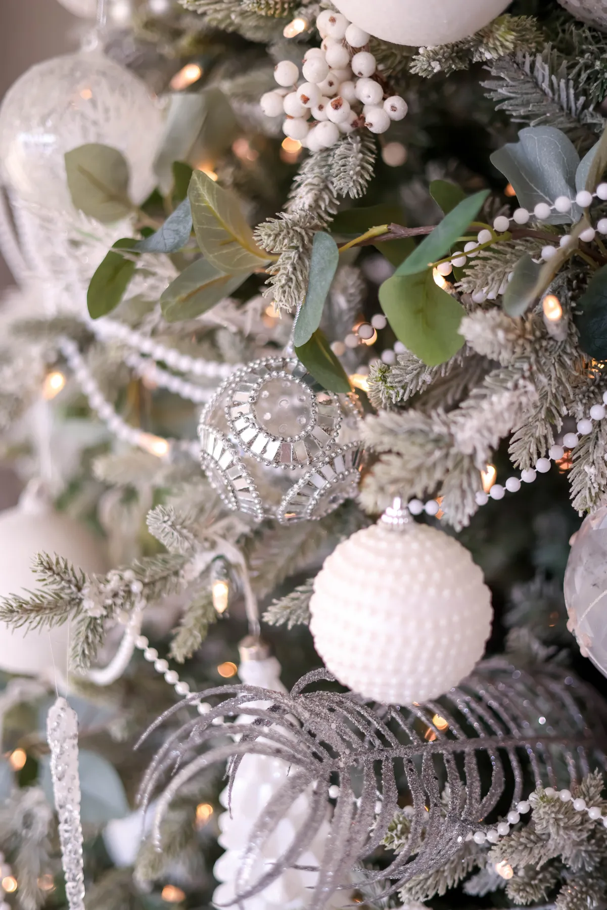 Close-up of a beautifully decorated Christmas tree with silver and white ornaments.