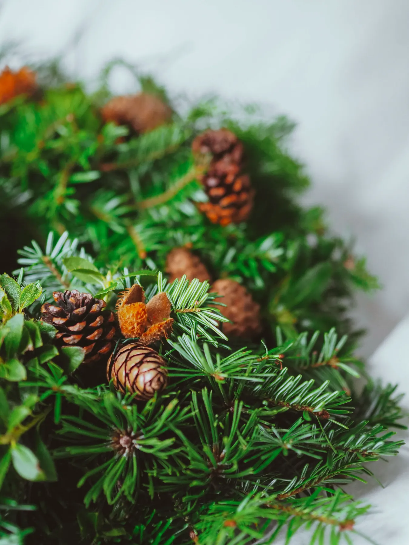 Close-up of a decorative evergreen wreath with pine cones for Christmas.