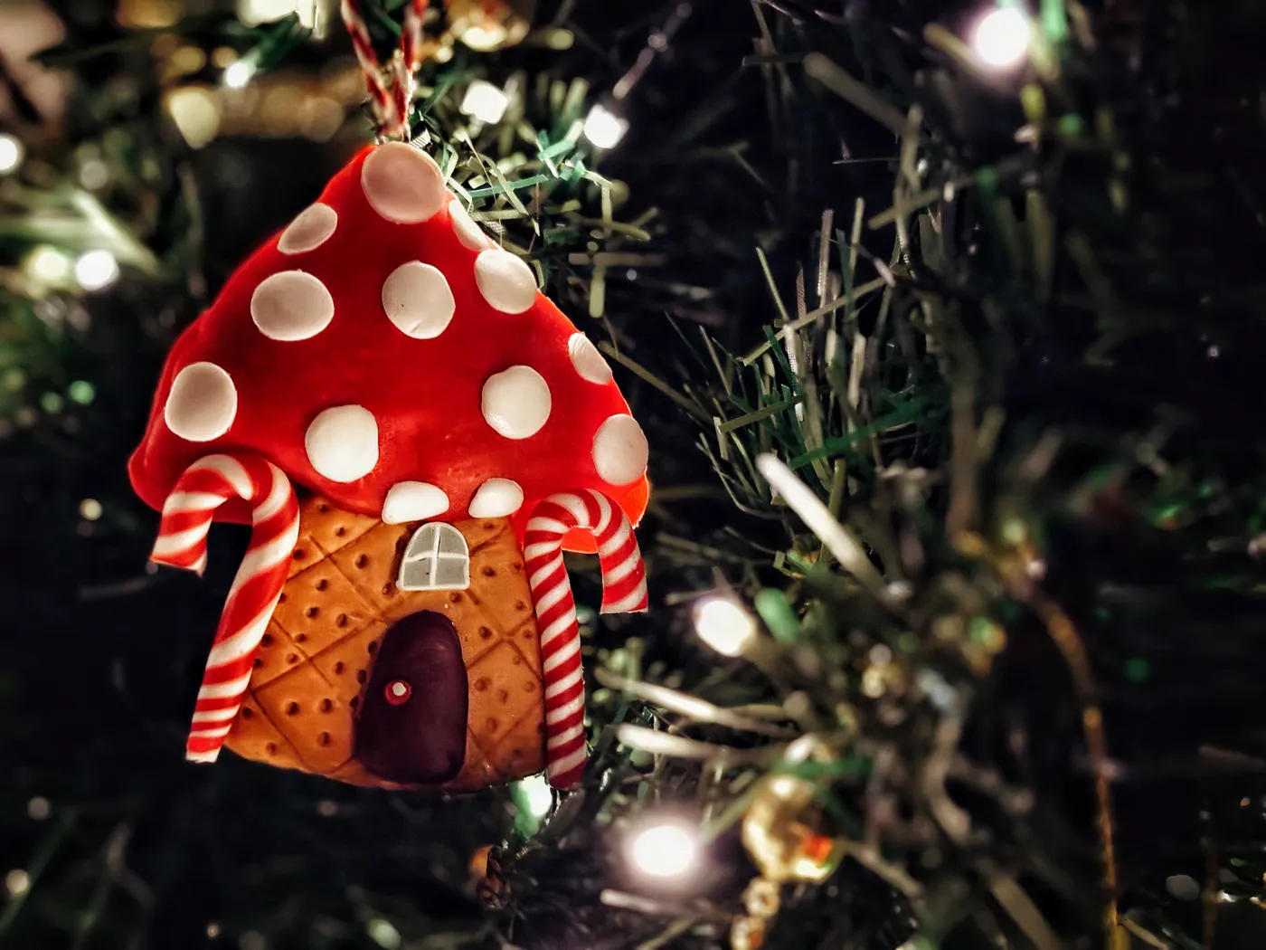 Close-up of a whimsical mushroom ornament with candy cane details on a Christmas tree.