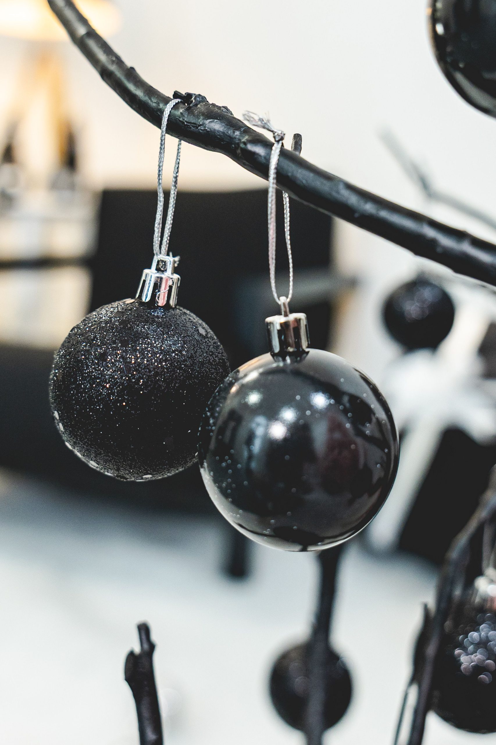 Close-up of black Christmas ornaments hanging on a modern branch.
