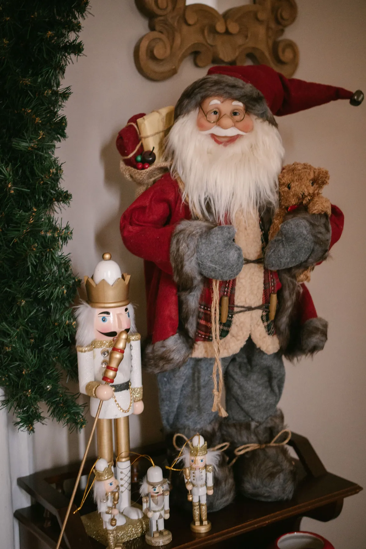 Cozy indoor Christmas scene featuring Santa Claus figure, nutcracker, and holiday decorations.