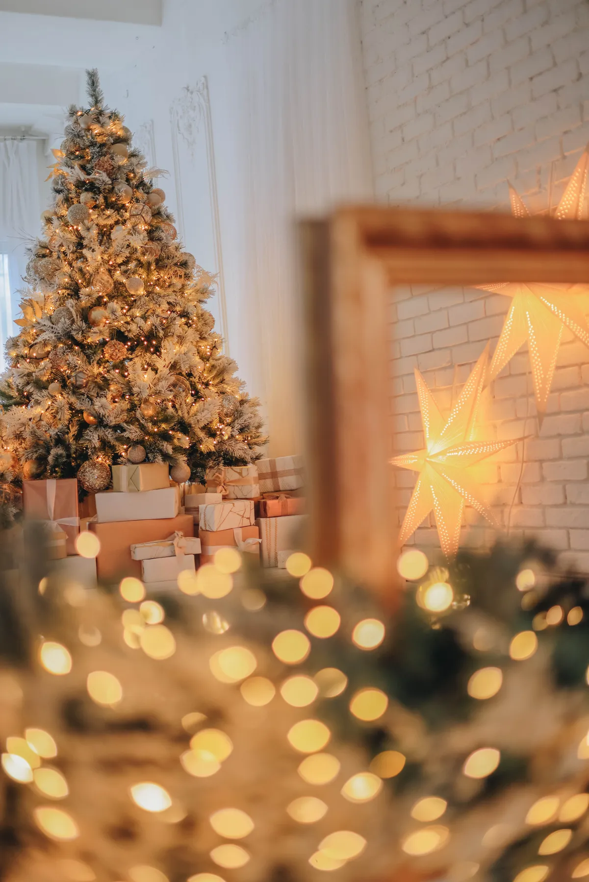 Cozy indoor scene of a decorated Christmas tree with glowing lights and star ornaments.