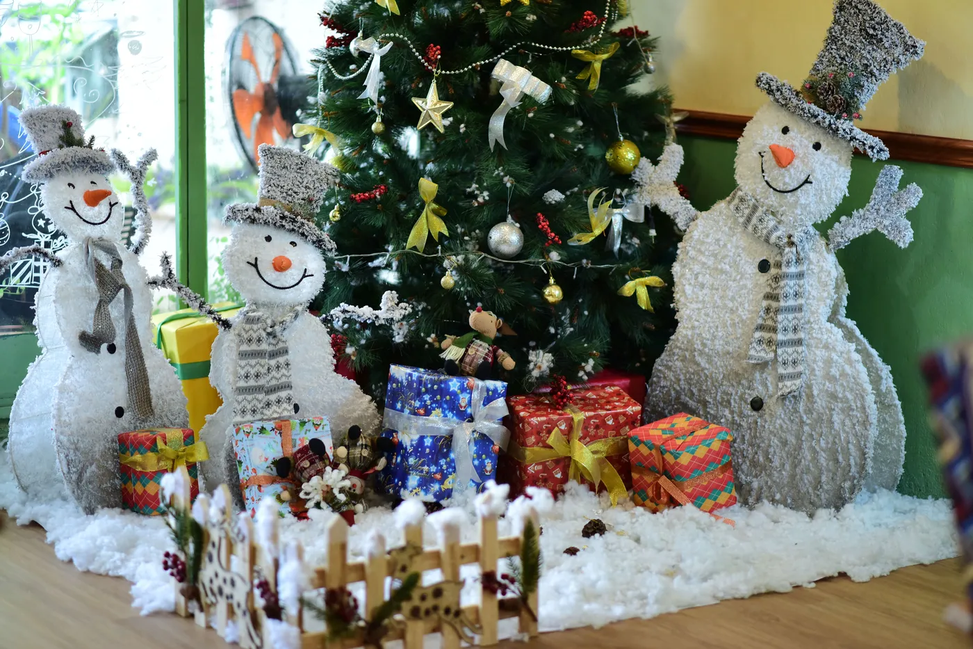Cozy winter scene with snowmen and a decorated Christmas tree.