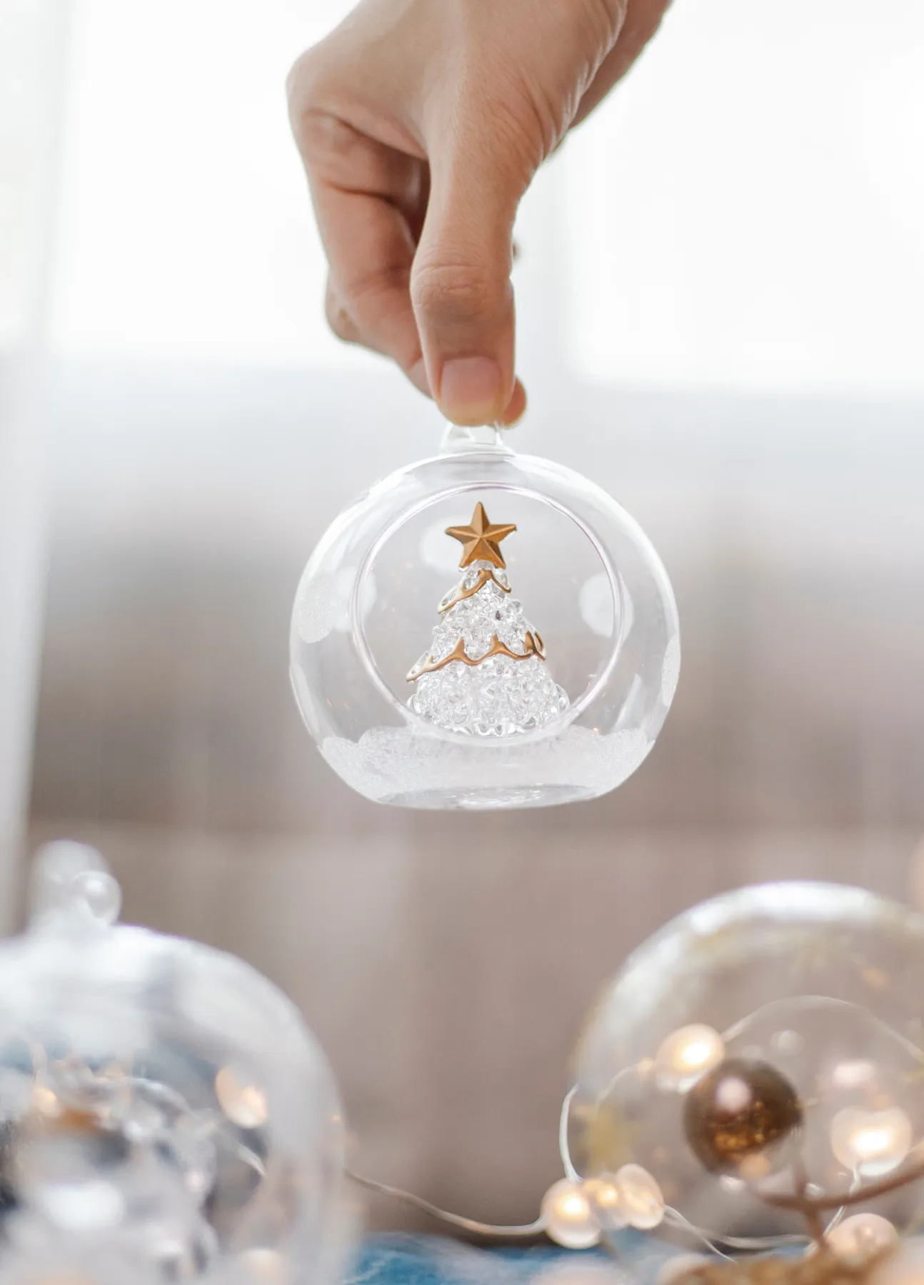 Crop anonymous person demonstrating decorative transparent glass ball with tree for Christmas celebration