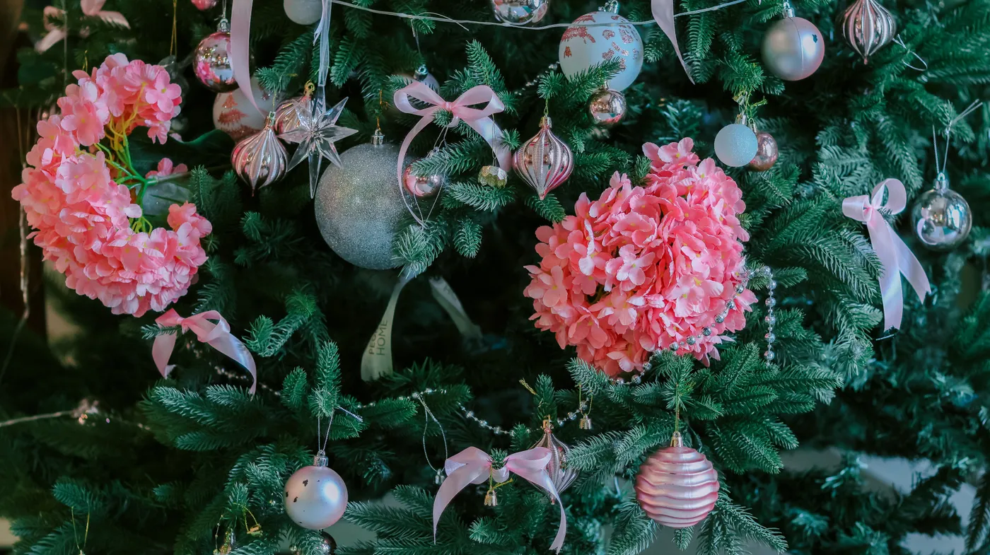Decorative Christmas tree adorned with pink flowers and ornaments, creating a festive atmosphere.