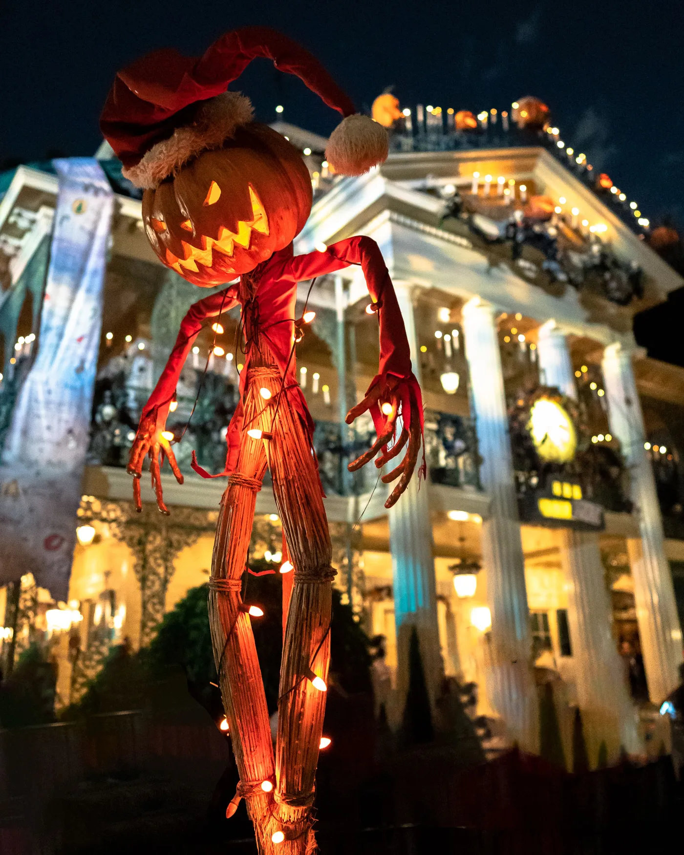 Eerie Halloween display with pumpkin figure and haunted house illumination under a night sky.
