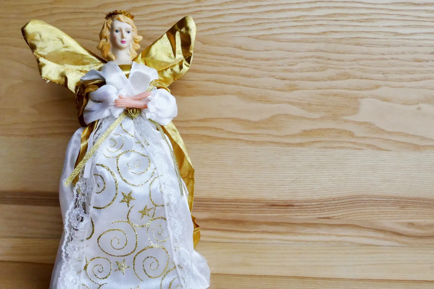 Elegant golden angel figurine with intricate gold detailing on a wooden surface.