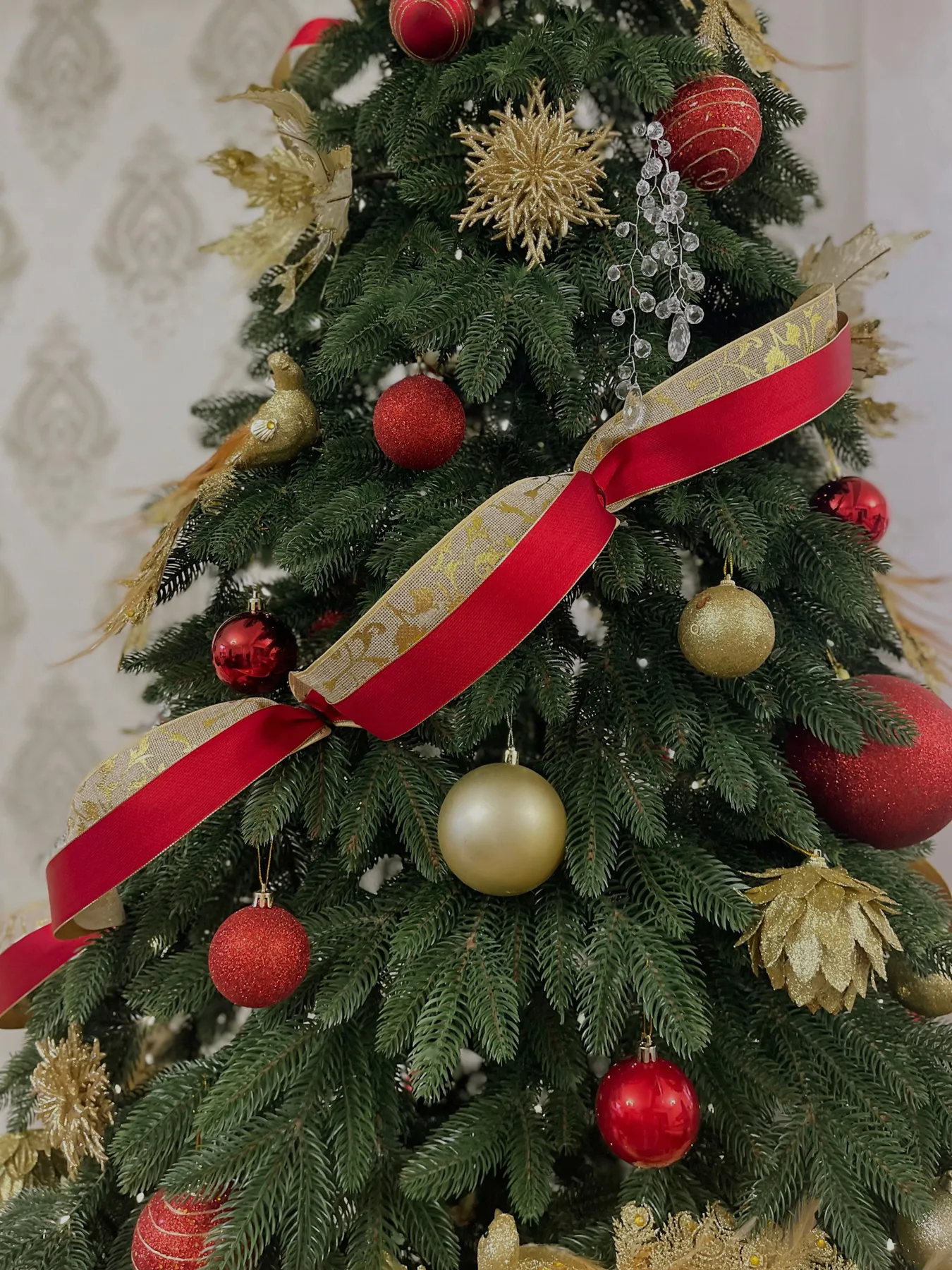Festive Christmas tree adorned with red and gold ornaments, ribbons, and decorations.