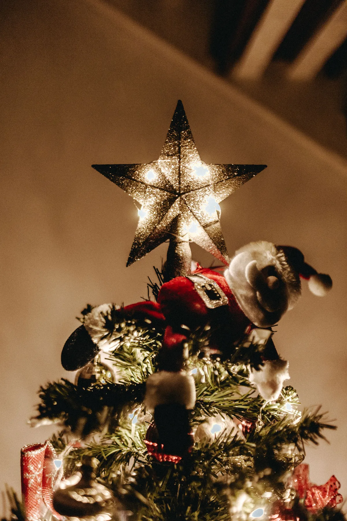 Glistening Christmas star and decoration atop a tree, creating a warm holiday ambiance.