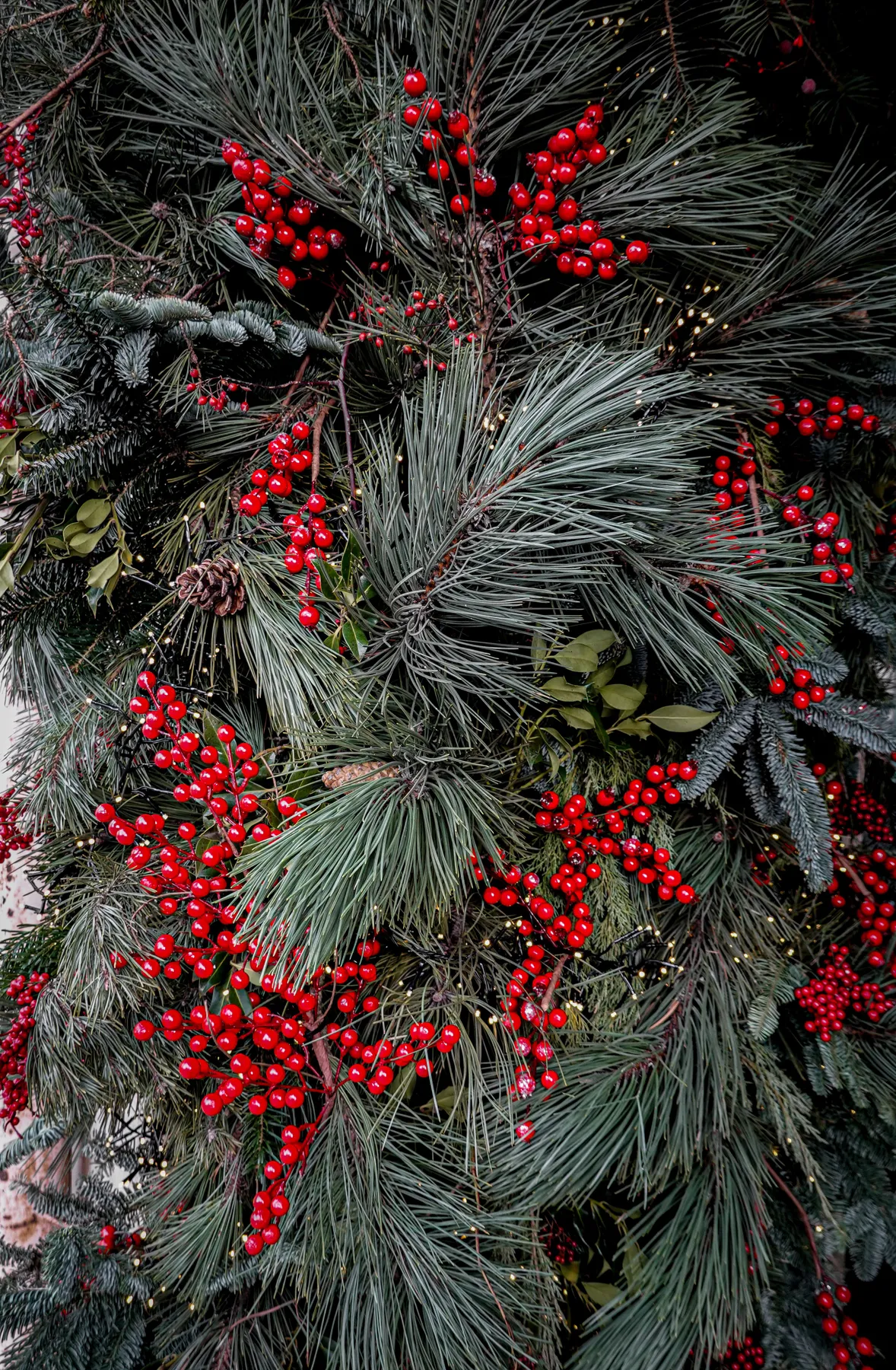 Lush Christmas decoration with evergreen branches and vibrant red berries, evoking a festive winter atmosphere.