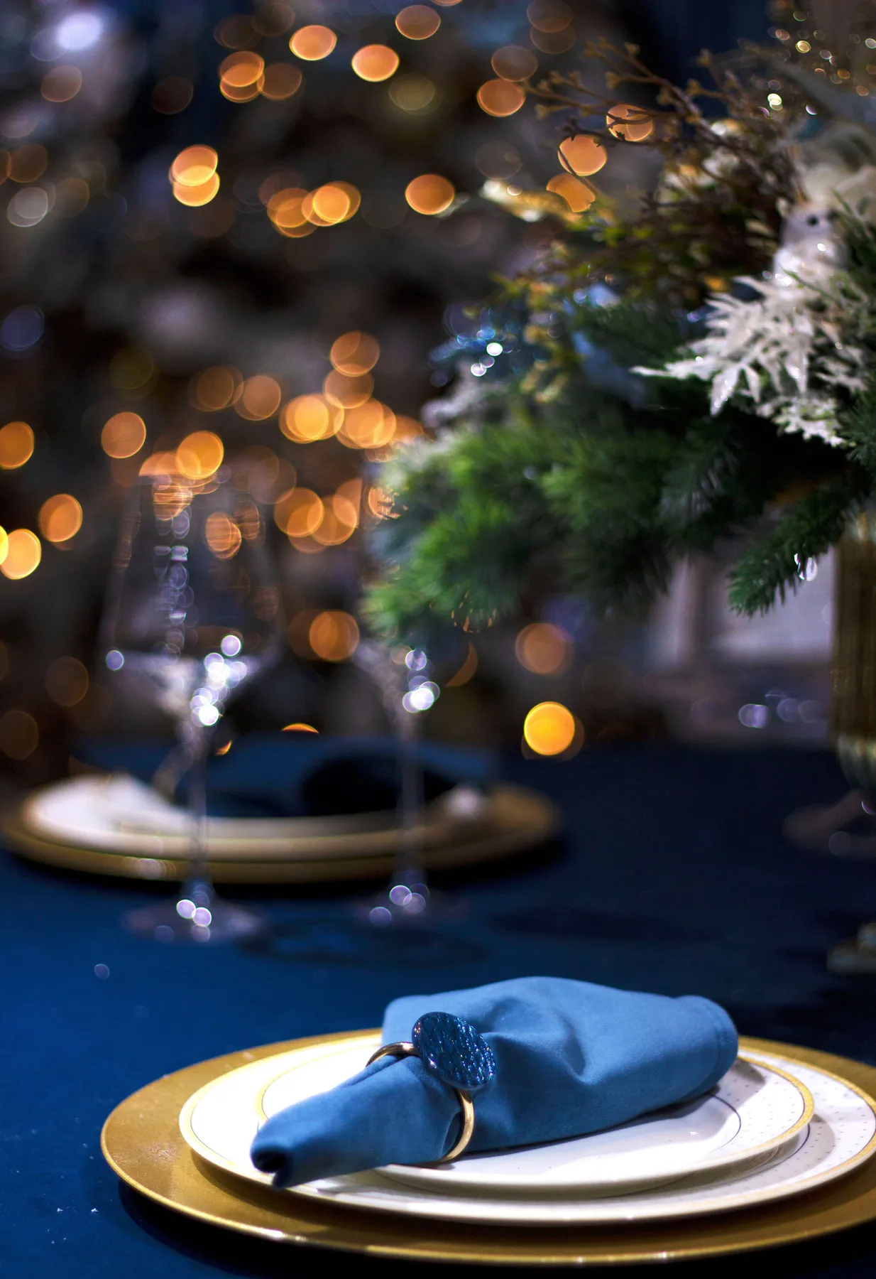 Luxurious dining table set for a festive occasion with warm bokeh lights and elegant decoration.