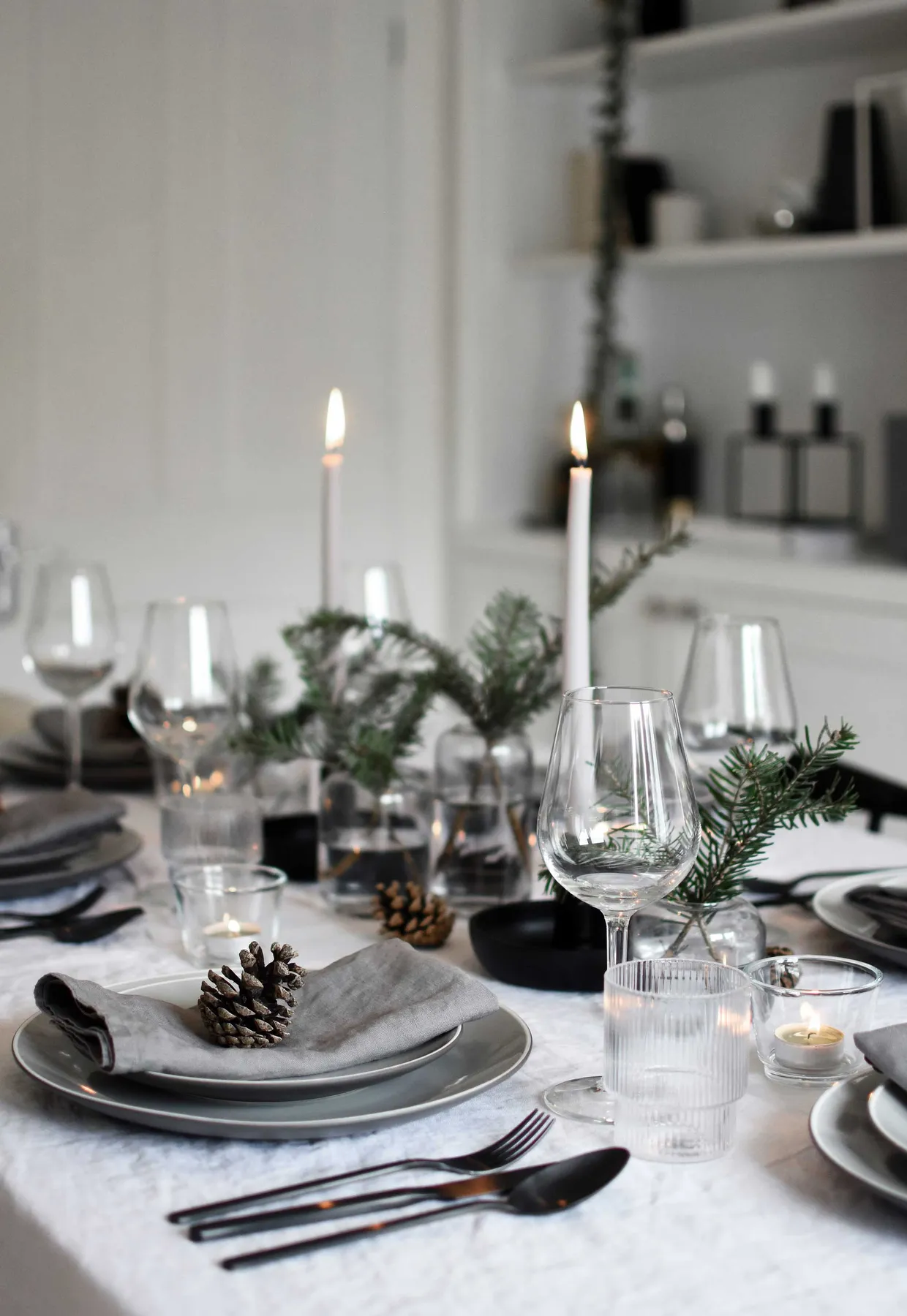 Minimalist Christmas table styling with fir, candles & pine cones |