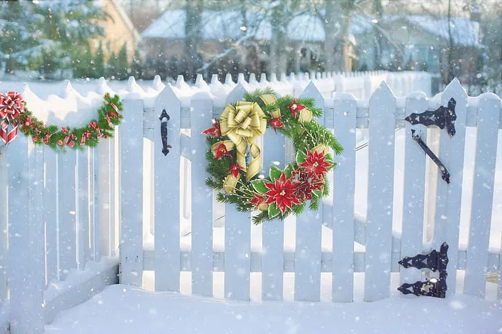 Royalty-Free photo: Green and red Christmas wreath on white wooden fence |  PickPik