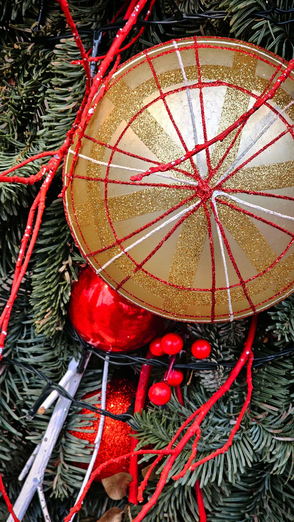Vibrant close-up of Christmas decorations with red and gold ornaments, pine branches.