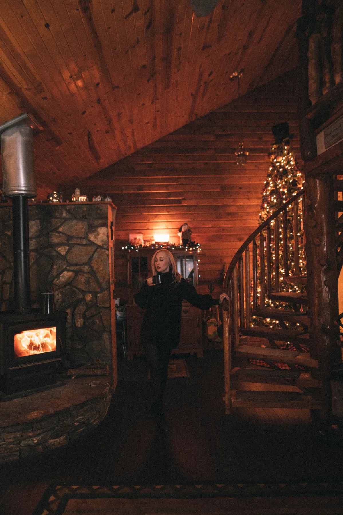 Warm and inviting cabin interior featuring a Christmas tree and fireplace. Perfect holiday setting.
