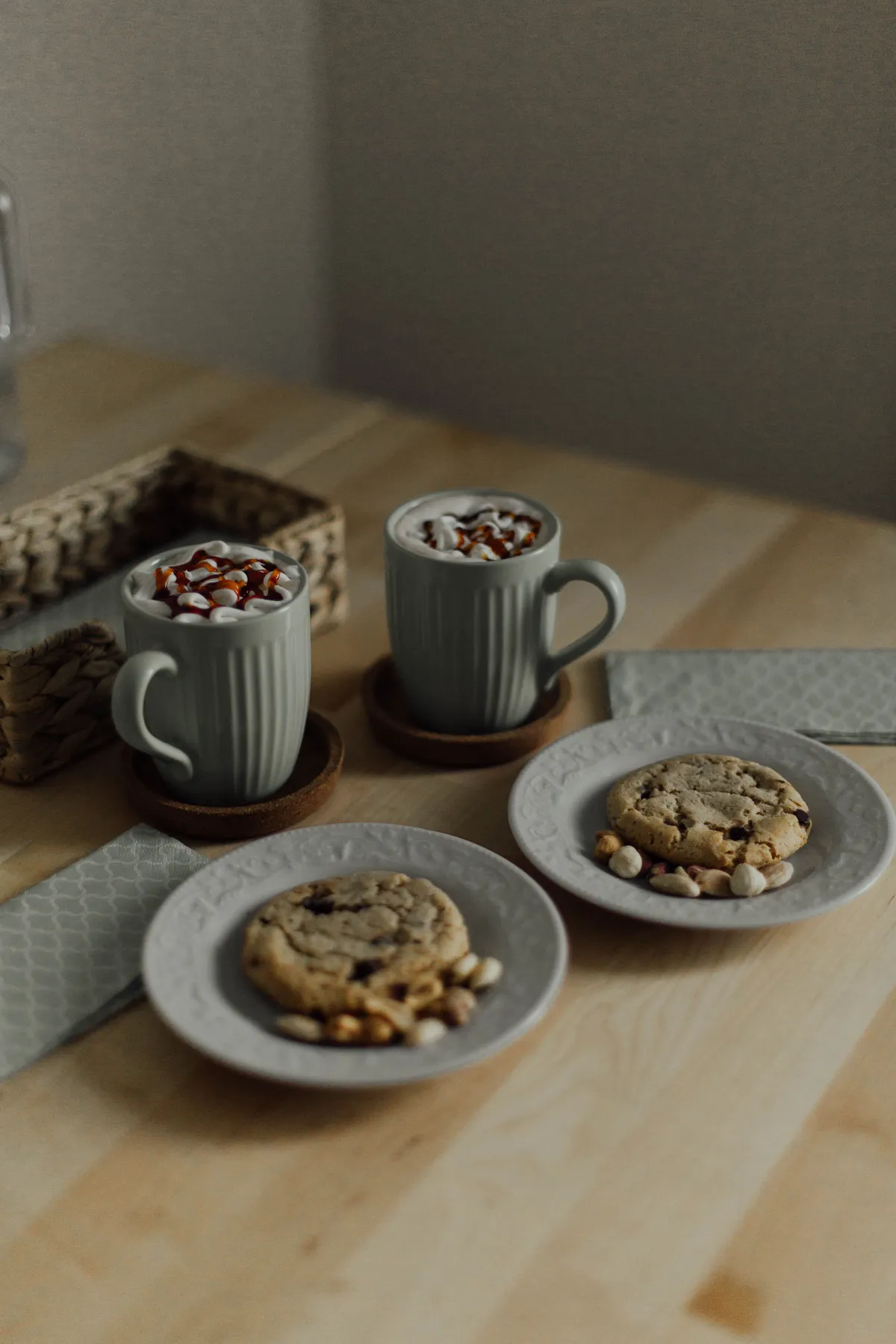 Warm mugs of hot chocolate with cookies on a wooden table, perfect for a cozy treat.